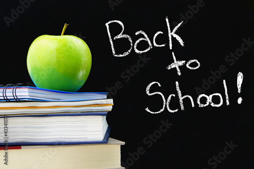 Photo: Back to School written on blackboard, books and apple in front Back to School written on blackboard, books and apple in front