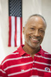 Smiling African American man standing near American flag