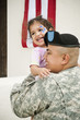 Hispanic soldier holding daughter in front of American flag