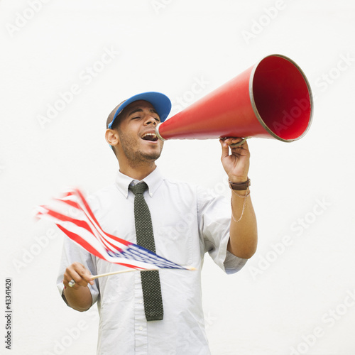 Photo: Hispanic man waving American flag and talking into megaphone Hispanic man waving American flag and talking into megaphone