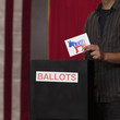 Voter putting ballot into ballot box at polling place