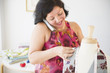 Hispanic seamstress talking on telephone and working