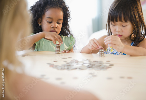 Photo: Girls stacking coins together Girls stacking coins together