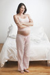 Pregnant Caucasian woman standing in bedroom