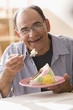 Senior Hispanic man eating birthday cake