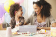 Mixed race mother watching daughter opening birthday present