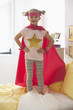 Caucasian girl dressed as superhero playing on bed