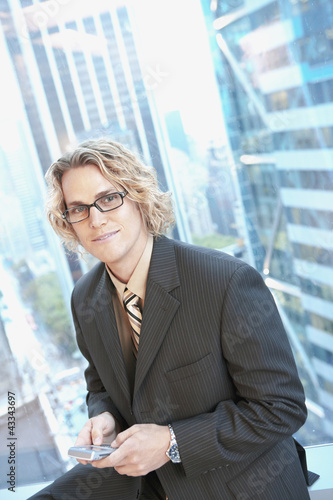 Photo: Caucasian businessman text messaging on cell phone Caucasian businessman text messaging on cell phone