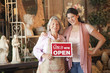 Hispanic business owners holding open sign in front of shop