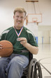 Caucasian man in wheelchair holding basketball medal