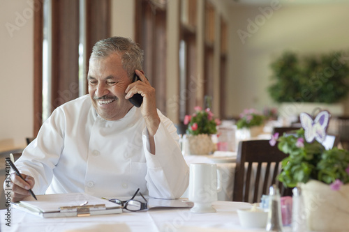 Photo: Hispanic chef working on paperwork in restaurant Hispanic chef working on paperwork in restaurant
