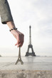 Hispanic woman holding a souvenir Eiffel Tower near the actual Eiffel Tower