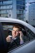 Caucasian businessman drinking coffee and talking on cell phone in car