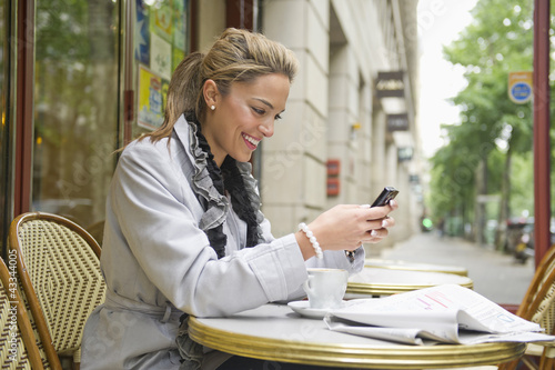 Photo: Hispanic woman using cell phone in outdoor cafe Hispanic woman using cell phone in outdoor cafe