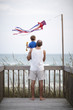 Father holding son on deck near ocean