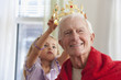 Caucasian girl putting crown on grandfather's head