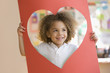 Grinning mixed race boy looking through heart-shaped hole