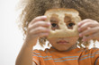 Mixed race boy looking through holes in slice of bread