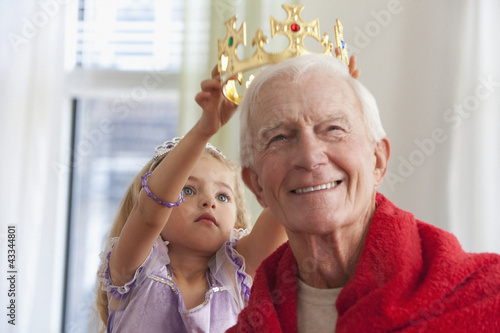 Photo: Caucasian girl putting crown on grandfather's head Caucasian girl putting crown on grandfather's head