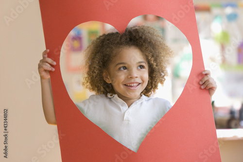 Photo: Grinning mixed race boy looking through heart-shaped hole Grinning mixed race boy looking through heart-shaped hole