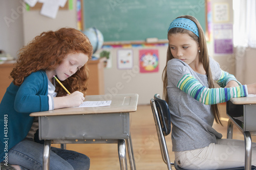 Photo: Girl trying to copy off of student's paper in classroom Girl trying to copy off of student's paper in classroom