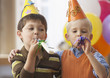Caucasian boys blowing noise makers at party