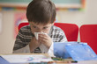 Caucasian boy blowing nose in classroom