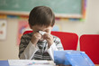 Caucasian boy blowing nose in classroom