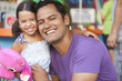 Smiling Hispanic father hugging daughter
