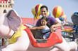 Hispanic father and daughter riding amusement park ride