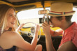 Woman taking picture of friend driving old-fashioned car