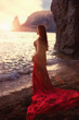 The beautiful red-haired girl poses on a sandy beach