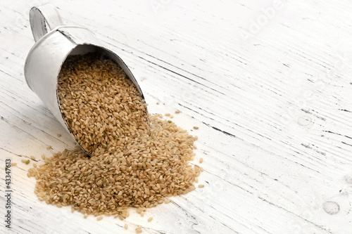 Photo: Scoop of Brown Rice on Rustic White Timber Scoop of Brown Rice on Rustic White Timber