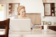 Hispanic woman using laptop in kitchen