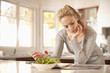 Hispanic woman eating salad and reading magazine