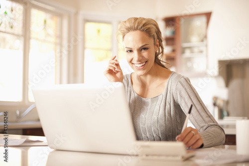 Photo: Hispanic woman using laptop in kitchen Hispanic woman using laptop in kitchen