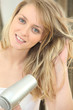 Blonde woman using a hairdryer