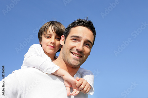 Foto: Boy riding piggy back on his father's back Boy riding piggy back on his father's back