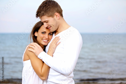 Photo: Couple Cuddling at the Beach Looking Happy Couple Cuddling at the Beach Looking Happy