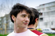 Two male friends stood outside back to back