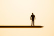 Figure of businessman balanced on pencil