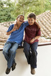 Hispanic boys sitting on roof hugging