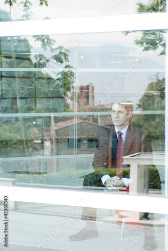 Photo: Hispanic businessman looking out window Hispanic businessman looking out window