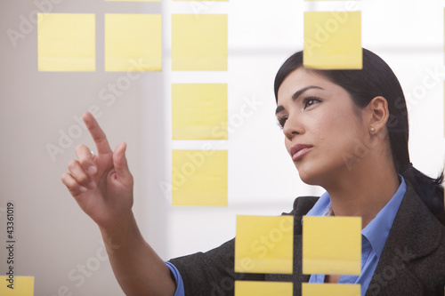 Photo: Hispanic businesswoman looking at sticky notes Hispanic businesswoman looking at sticky notes