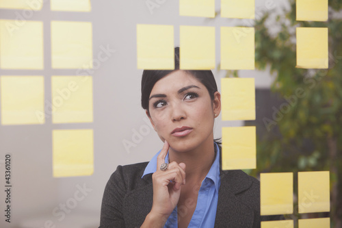 Photo: Hispanic businesswoman looking at sticky notes Hispanic businesswoman looking at sticky notes