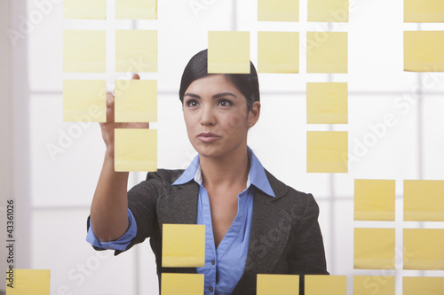 Photo: Hispanic businesswoman looking at sticky notes Hispanic businesswoman looking at sticky notes