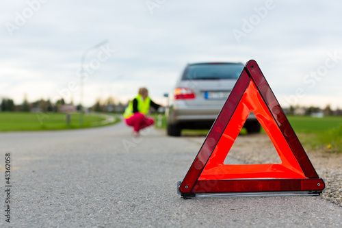 Foto: Junge Frau mit Warndreieck auf Straße Junge Frau mit Warndreieck auf Straße