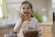 Photo: Mixed race girl frosting cake and licking fingers Mixed race girl frosting cake and licking fingers