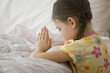 Caucasian girl kneeling by bed praying