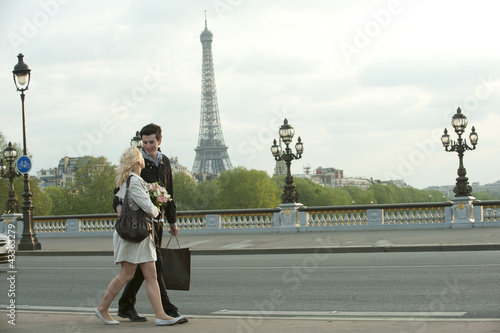 Photo: Caucasian couple walking across bridge with Eiffel Tower in background Caucasian couple walking across bridge with Eiffel Tower in background